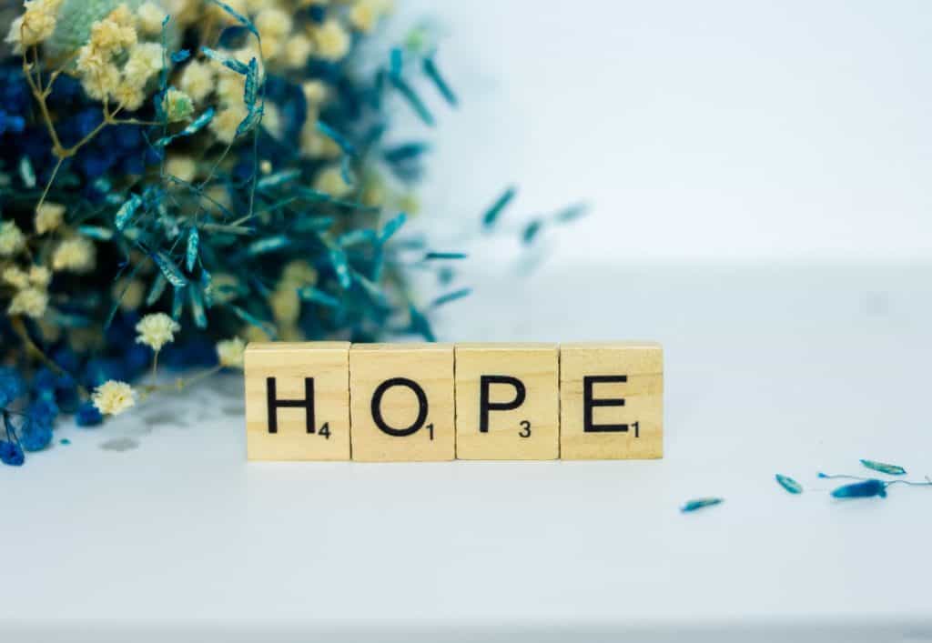 a wooden block that says hope next to a bouquet of flowers